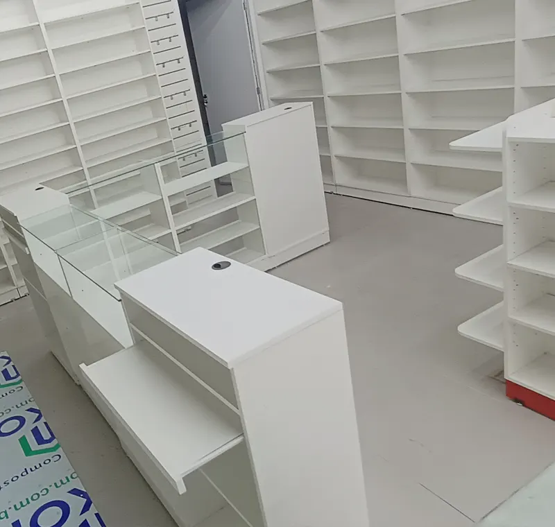 Estrutura de loja em montagem com balcões, vitrines e estantes brancas